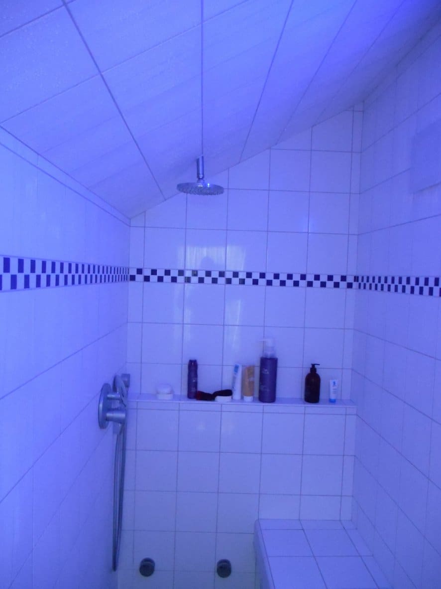 Hammam carrelé blanc avec frise bleue, éclairé en lumière bleue de chromothérapie