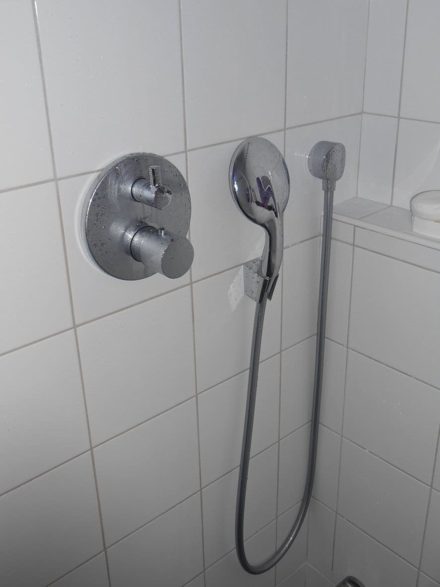Mitigeur thermostatique et douchette chromés dans un hammam carrelé