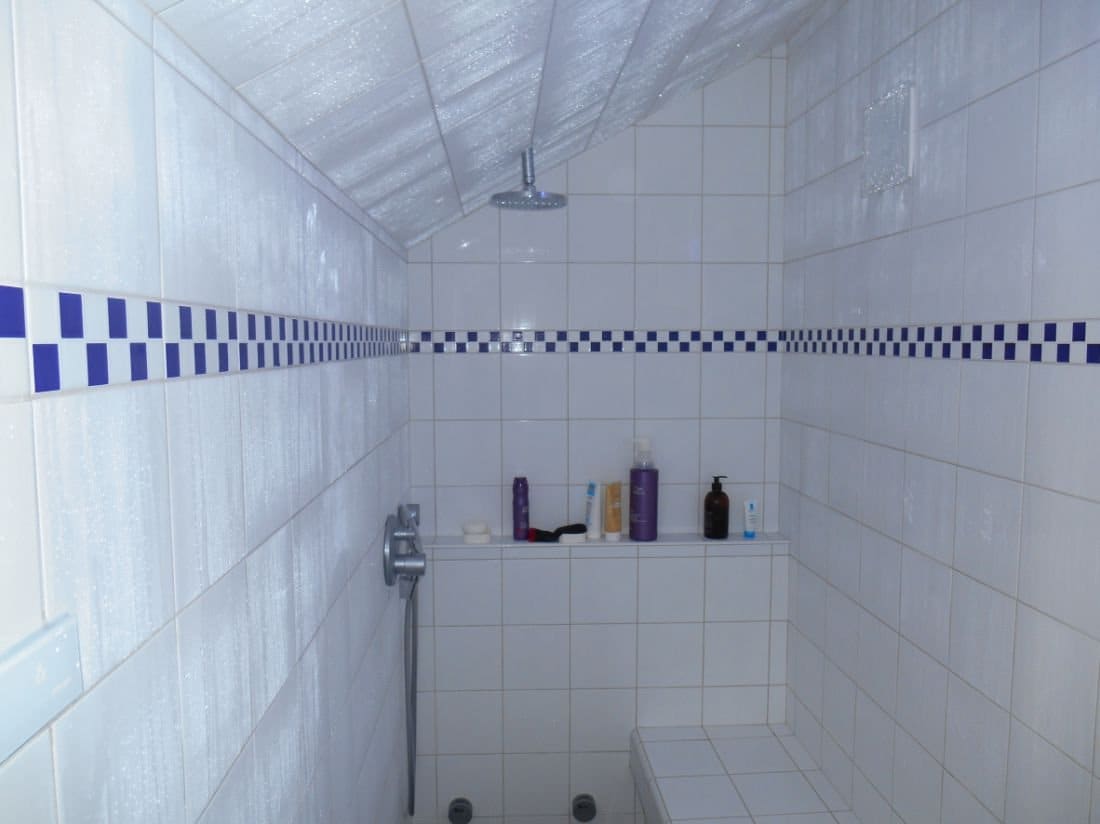 Hammam carrelé avec banc, niche de rangement et frise bleue